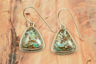 Genuine Sunnyside Turquoise set in Sterling Silver French Wire Earrings. The matrix on this rare stone is outstanding. The Sunnyside mine is located in northern Nevada near the town of Tuscarora in the Tuscarora mountain range. The mine is no longer in operation as it has become part of a gold mining operation and a privately owned ranch. The Sunnyside mine was mined mostly in the 70's. You won't find much of this great turquoise around anymore except for old stashes. Created by Navajo Artist Milton Lee. Signed. 
